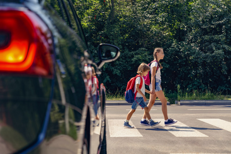 students crossing a crosswalk across a busy street